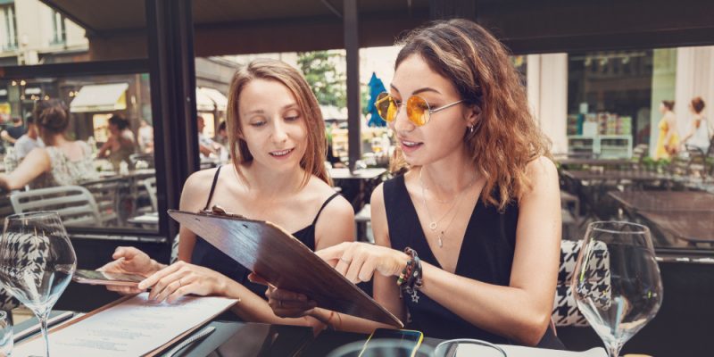 Duas mulheres jovens, olhando o cardápio de um restaurante