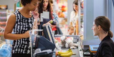 Mulher no caixa de um supermercado pagando a conta