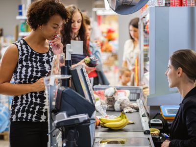 Mulher no caixa de um supermercado pagando a conta