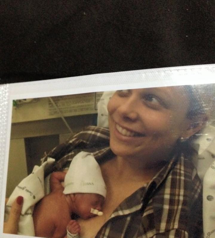 Mãe segurando bebê recém nascida no colo, com um sorriso