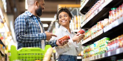 Casal jovem, sorridente, negros, fazem compras num supermercados